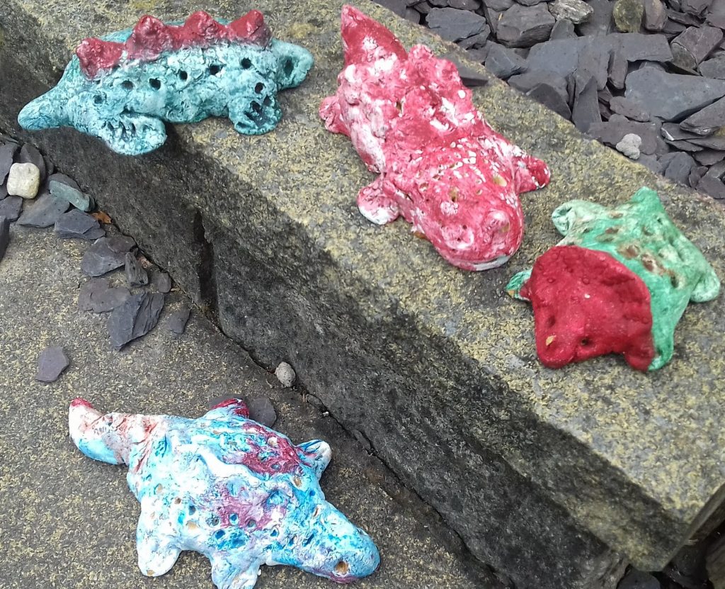 Photo of handmade salt dough dinosaurs on rocks.